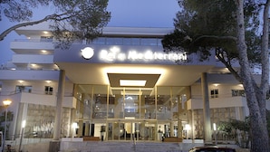 A modern hotel entrance with a glass facade, a prominent sign, and a staircase leading up to the entrance.