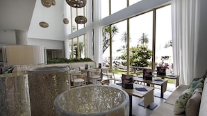 A modern hotel lobby with large windows, a seating area, and a decorative column.