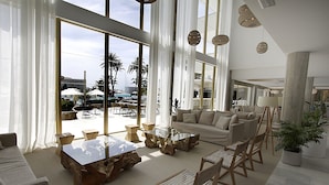 A spacious living area with a large glass table, comfortable seating, and a view of the outdoor pool area.
