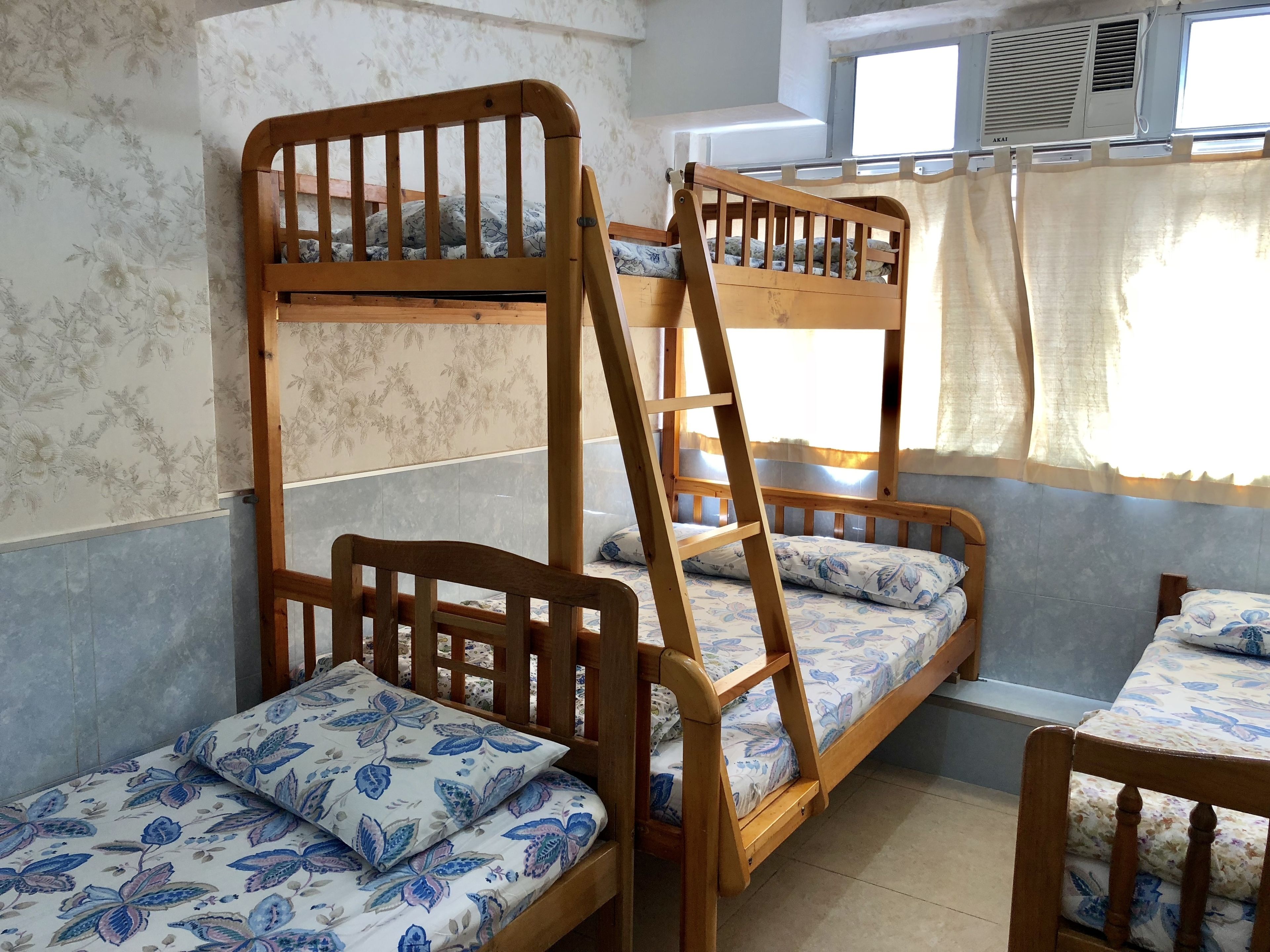 Une chambre avec des lits superposés, de la literie à motifs floraux et une fenêtre avec des rideaux.
