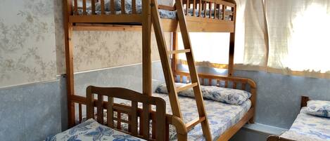 Une chambre avec des lits superposés, de la literie à motifs floraux et une fenêtre avec des rideaux.