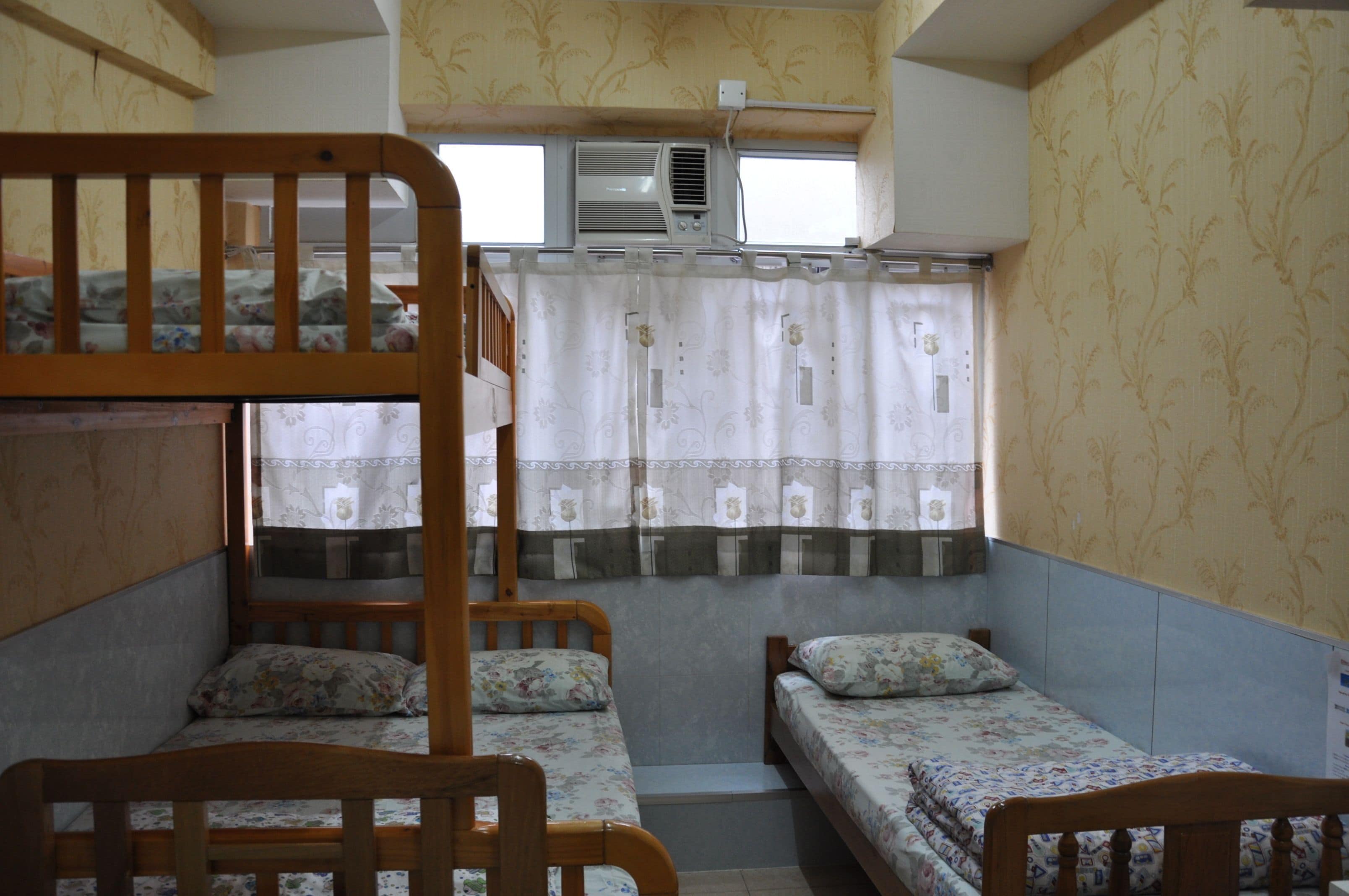 A room with bunk beds, a window with curtains, and an air conditioning unit.