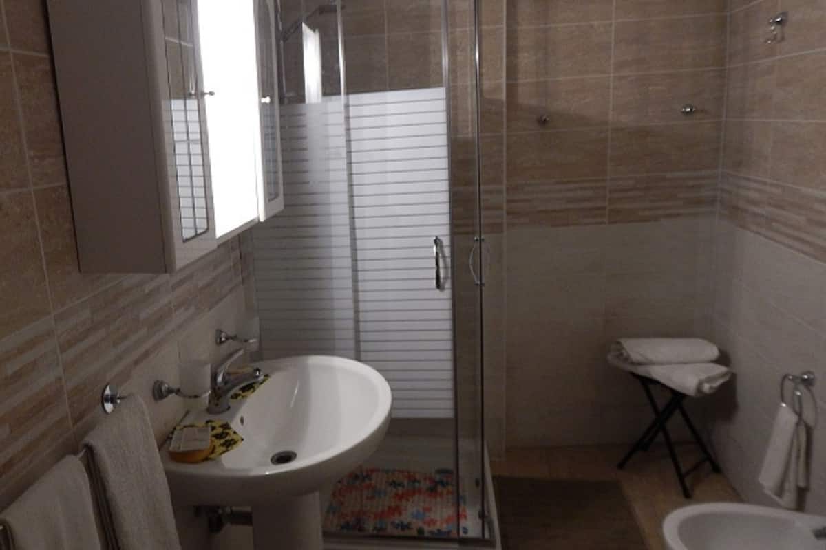 Un baño con un lavamanos blanco, una cabina de ducha de vidrio y un inodoro.