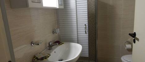 Un baño con un lavamanos blanco, un inodoro y una zona de ducha.