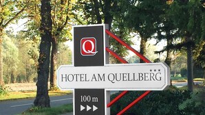 Un panneau de signalisation indiquant la direction à suivre pour se rendre à l’hôtel Am Quellberg, ainsi que la distance.