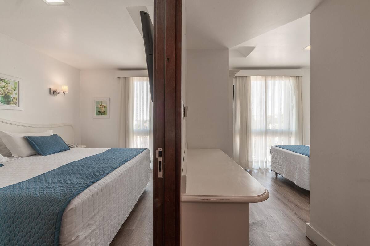 Habitación de hotel con dos camas, un escritorio pequeño y vistas a la ciudad.