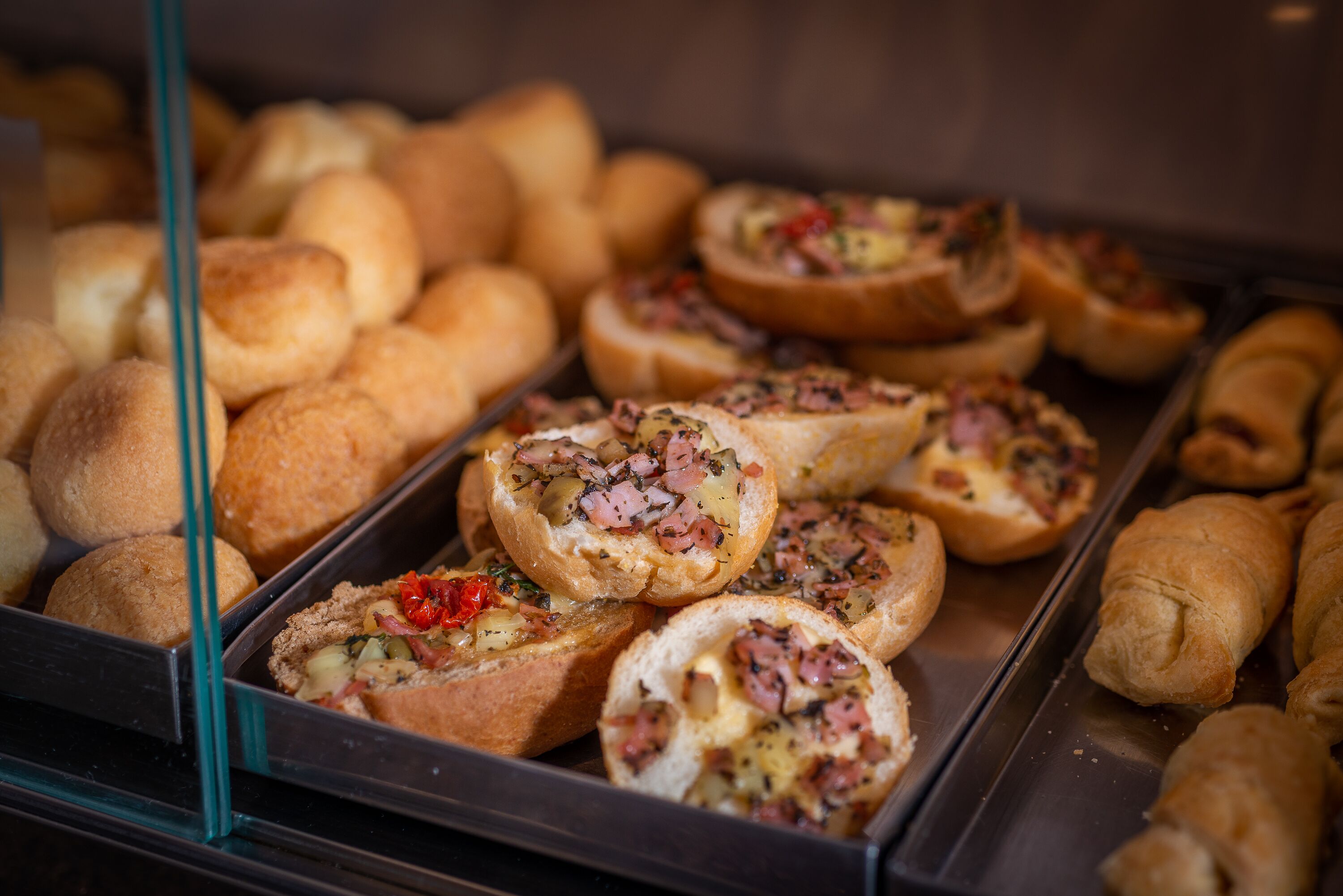 Una vitrina con diversas opciones de panadería, incluyendo bollos y panes rellenos.
