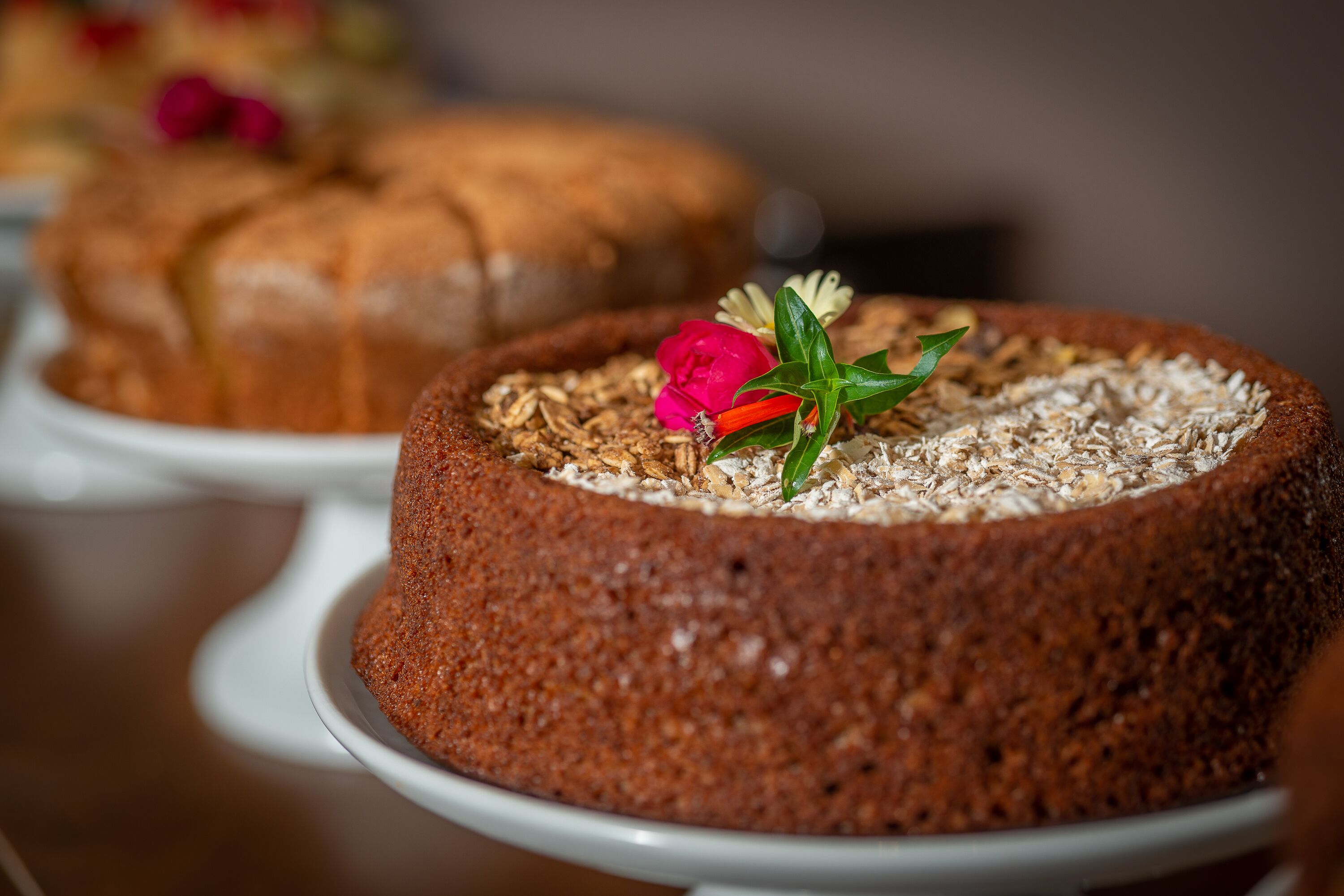 Ein runder Kuchen mit Haferflocken, verziert mit einer Blume und grünen Blättern.