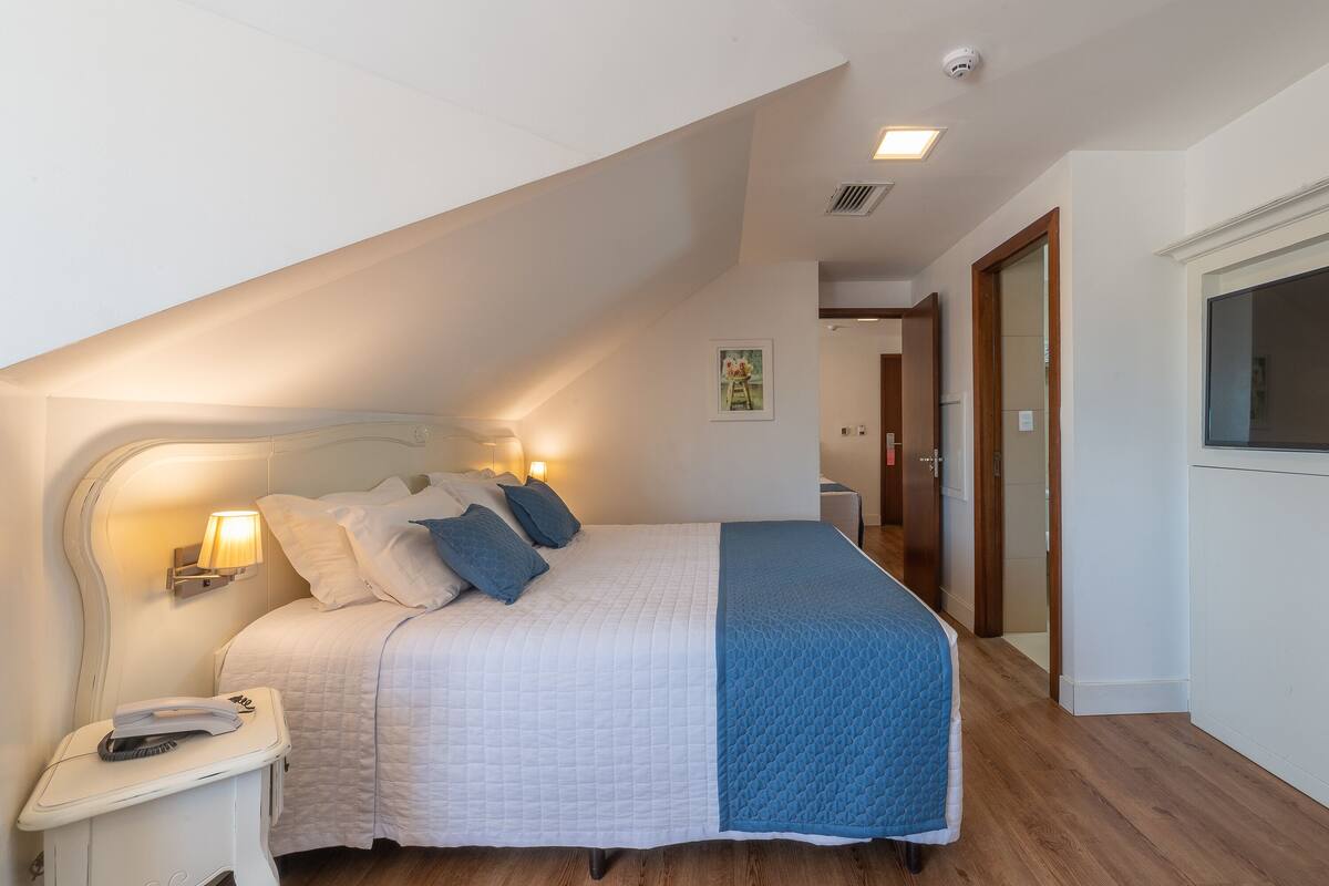 Un dormitorio con una cama, lámpara de noche y un teléfono en la mesita de noche.