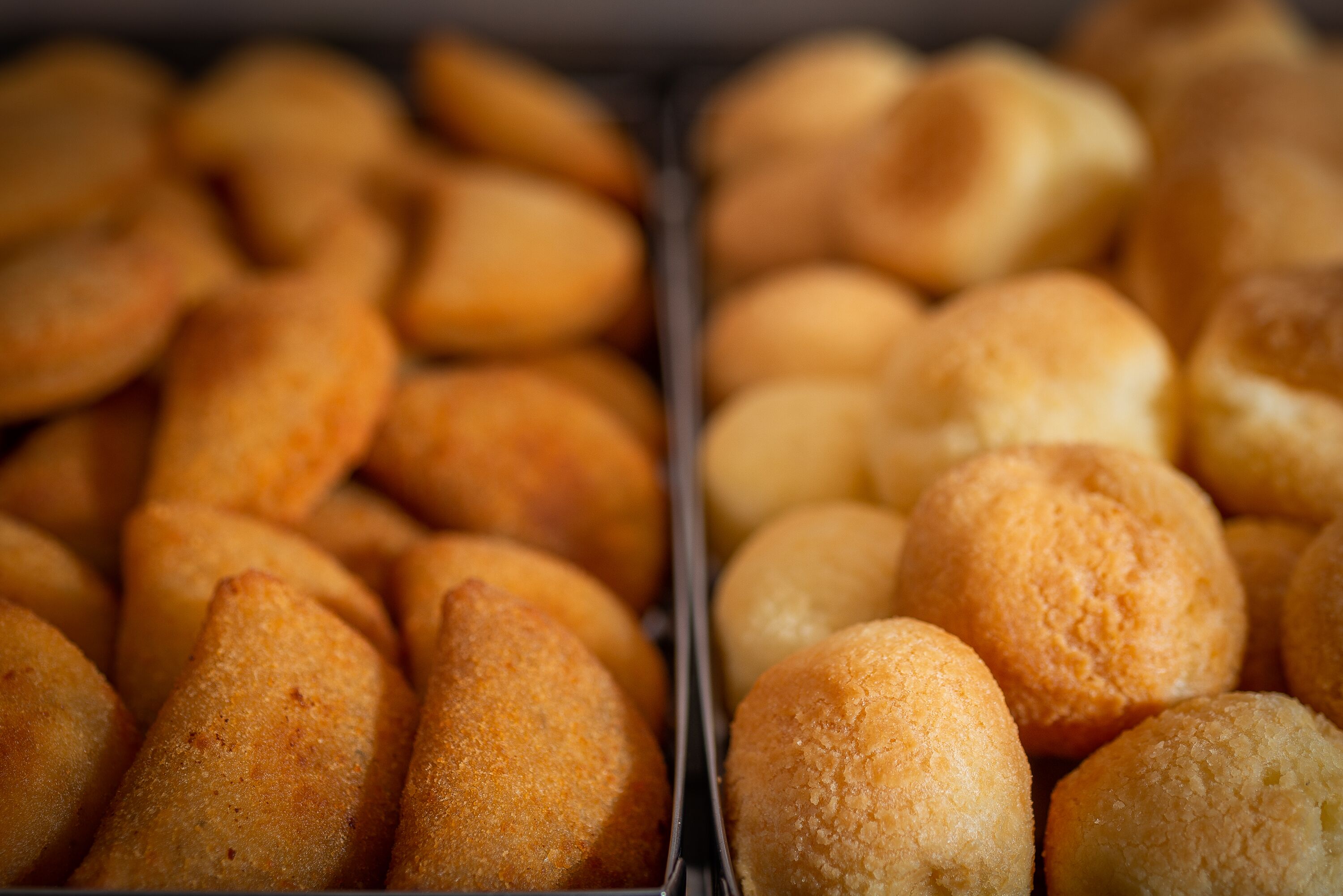 Una bandeja con pasteles dorados, probablemente un tipo de pan o producto horneado, dispuestos en un recipiente metálico.