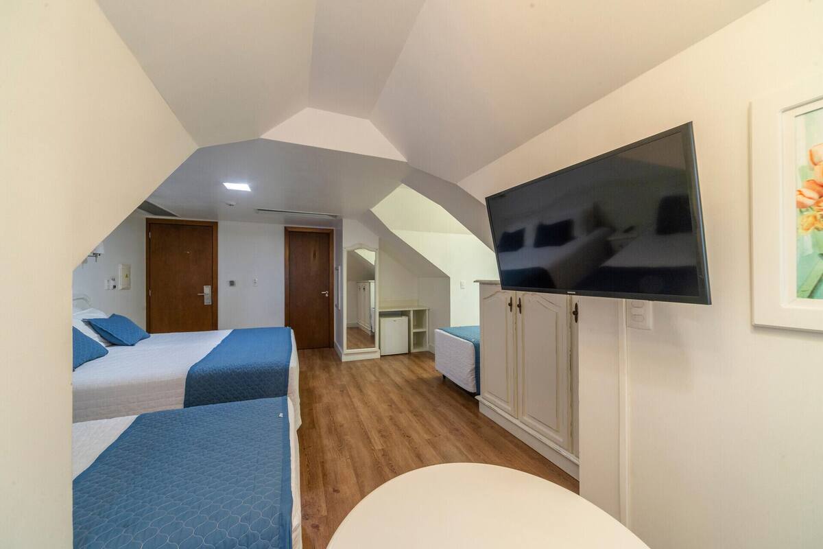 Una habitación con dos camas, televisión y una pequeña kitchenette.