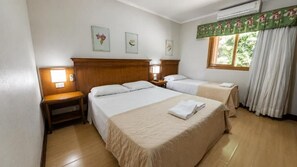 A hotel room with two beds, a wooden headboard, a nightstand, a window with curtains, and wall-mounted artwork. - Hanna Pórtico Gramado Hotel (Gramado)