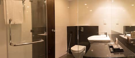 Un baño moderno con cabina de ducha de vidrio, inodoro y tocador con lavabo y espejo.