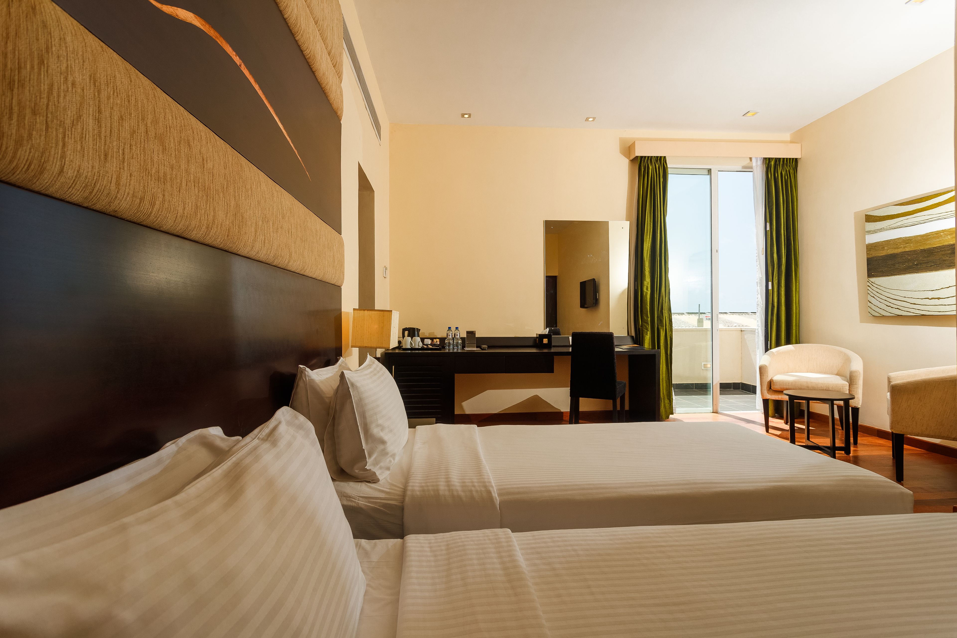Habitación de hotel con dos camas, un escritorio, una silla y vistas al exterior.