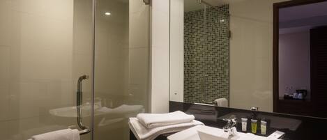 Un baño moderno con cabina de ducha de vidrio, un lavabo blanco y un espejo grande.