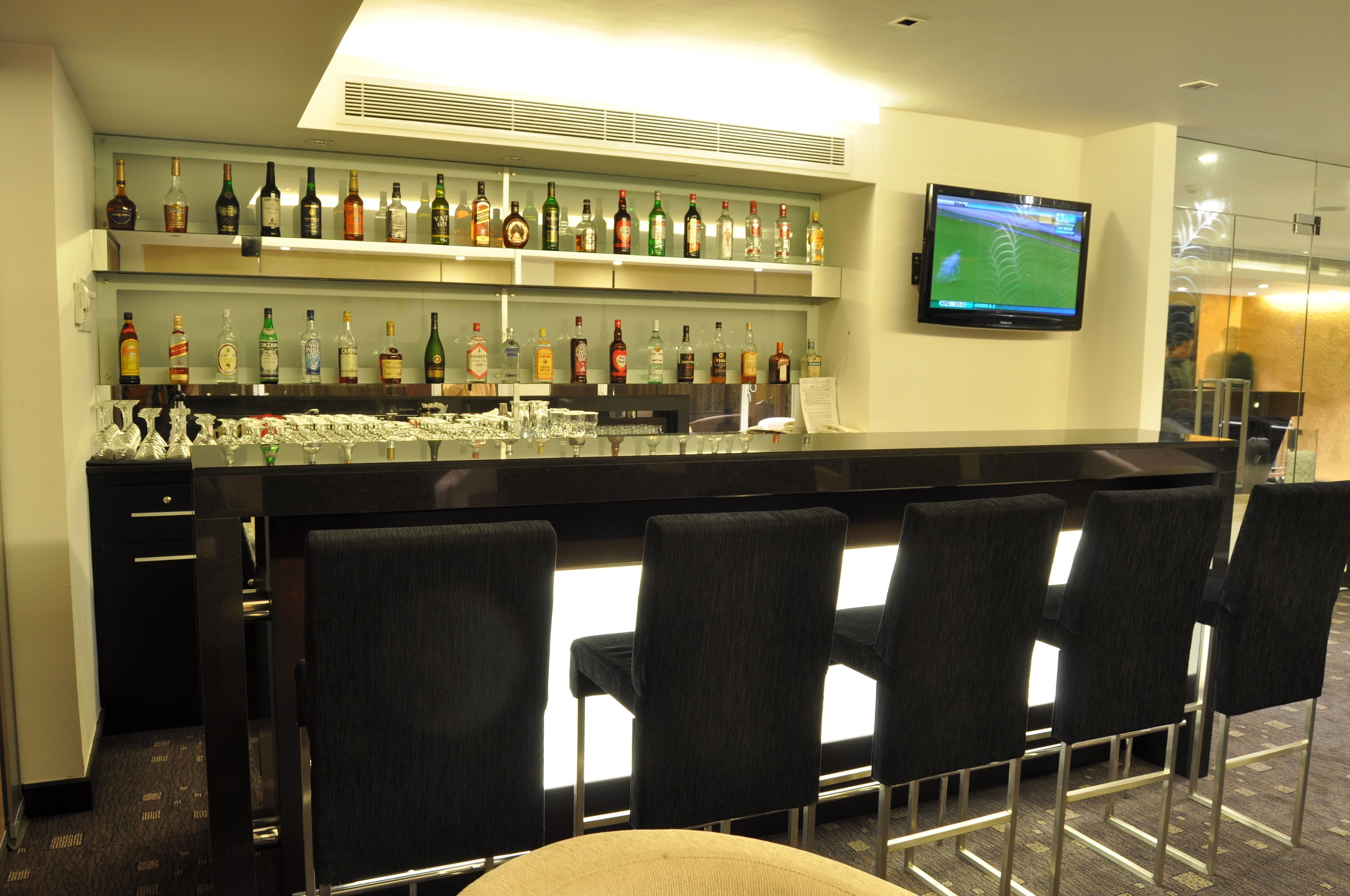 Un'area bar con diverse bottiglie di liquore, un televisore e posti a sedere al bancone.