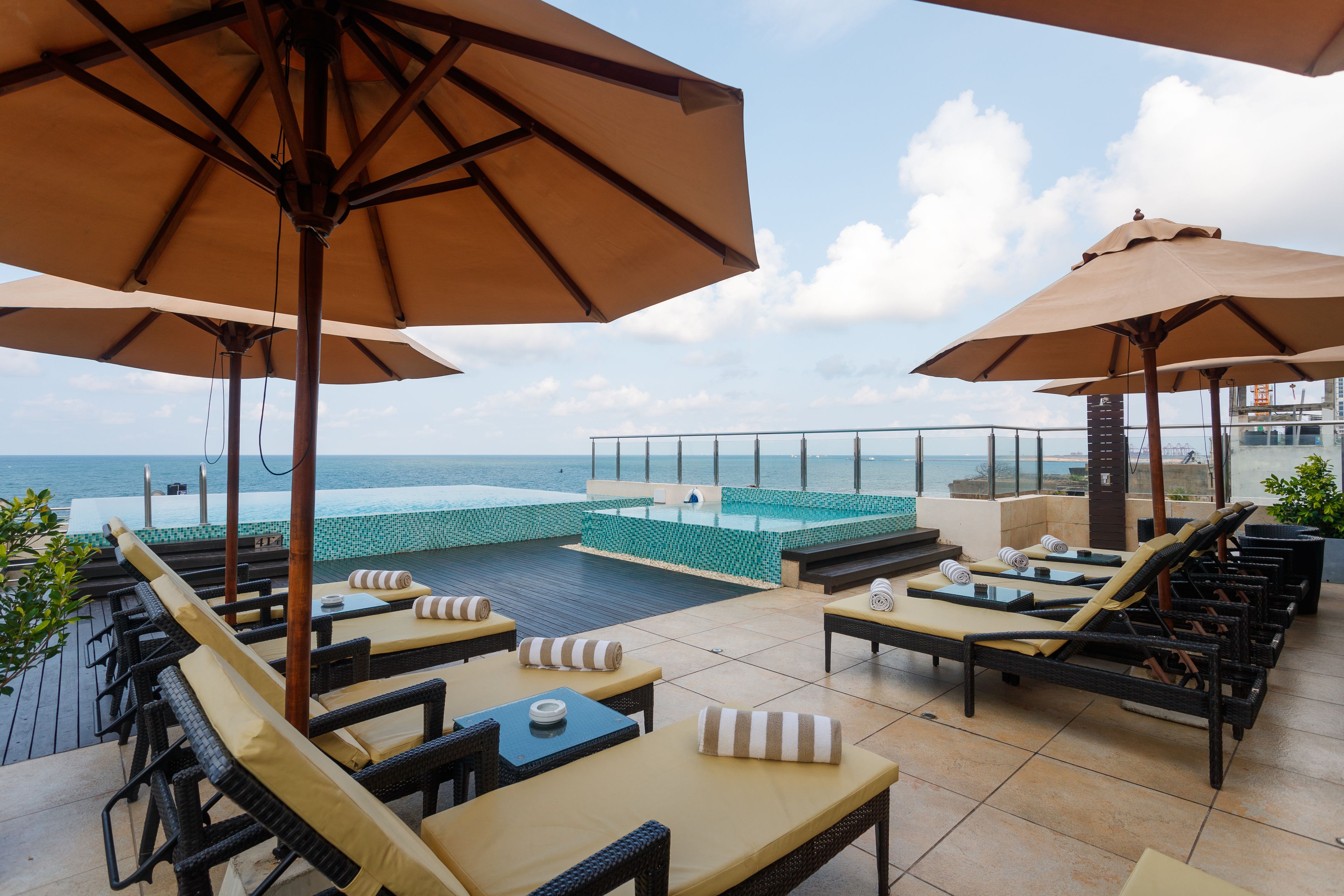 Una piscina al aire libre, sombrillas, sillones reclinables de piscina