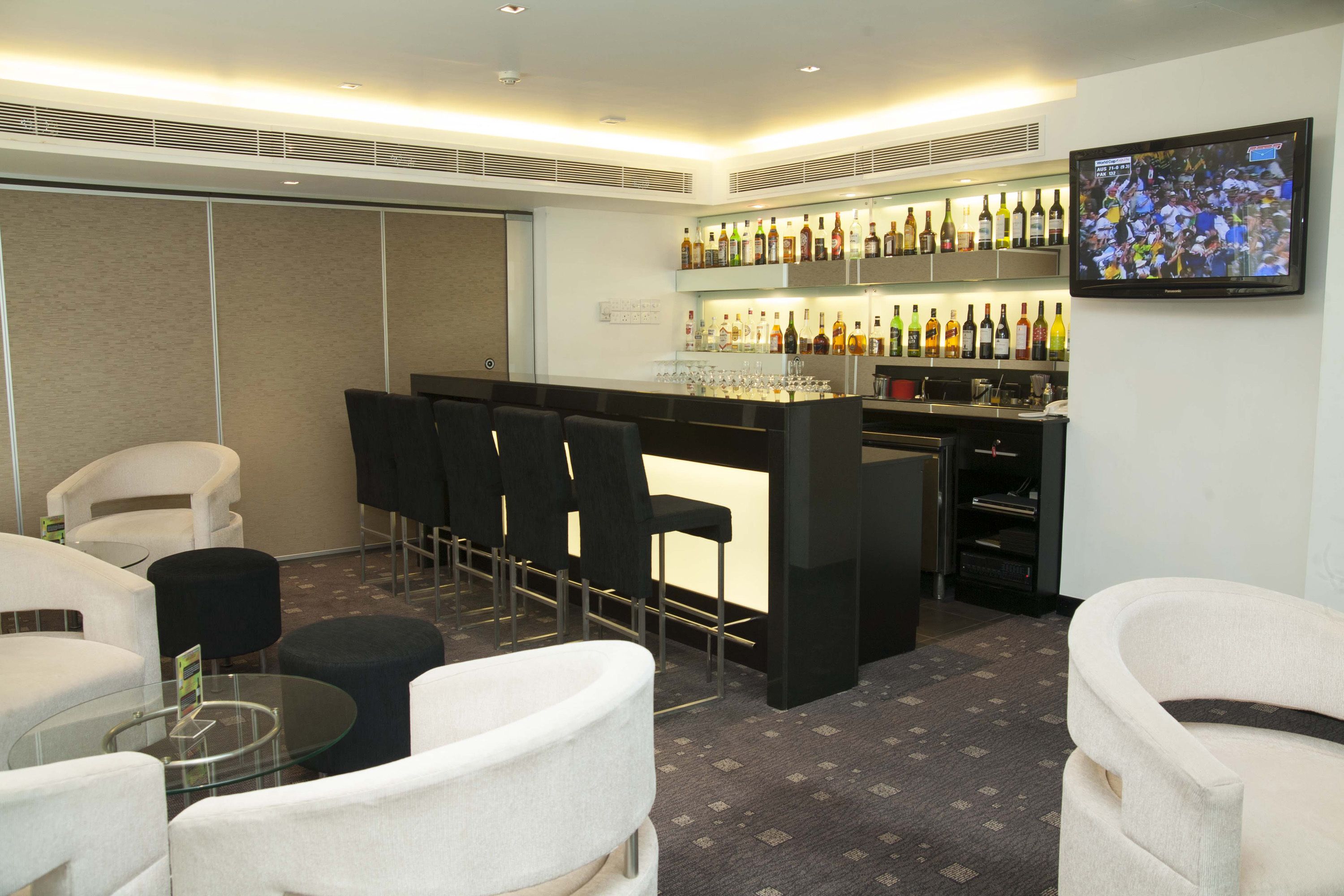 A modern bar area with seating and a television screen.