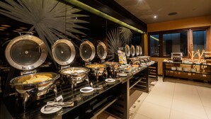 Disposição de buffet com várias estações de serviço, uma vitrine de vidro e uma grande janela ao fundo.
