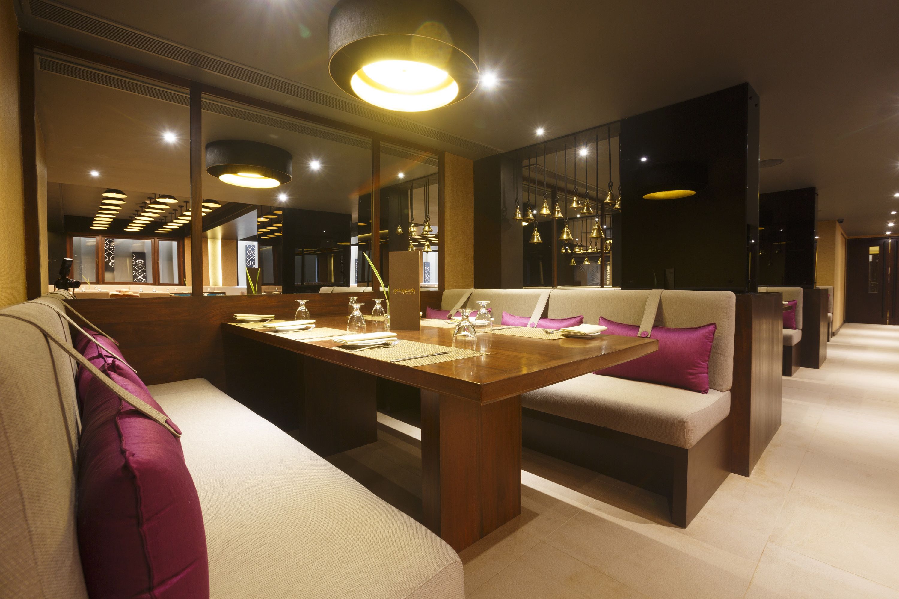 Un comedor moderno con una mesa de madera, asientos acolchados e iluminación colgante.