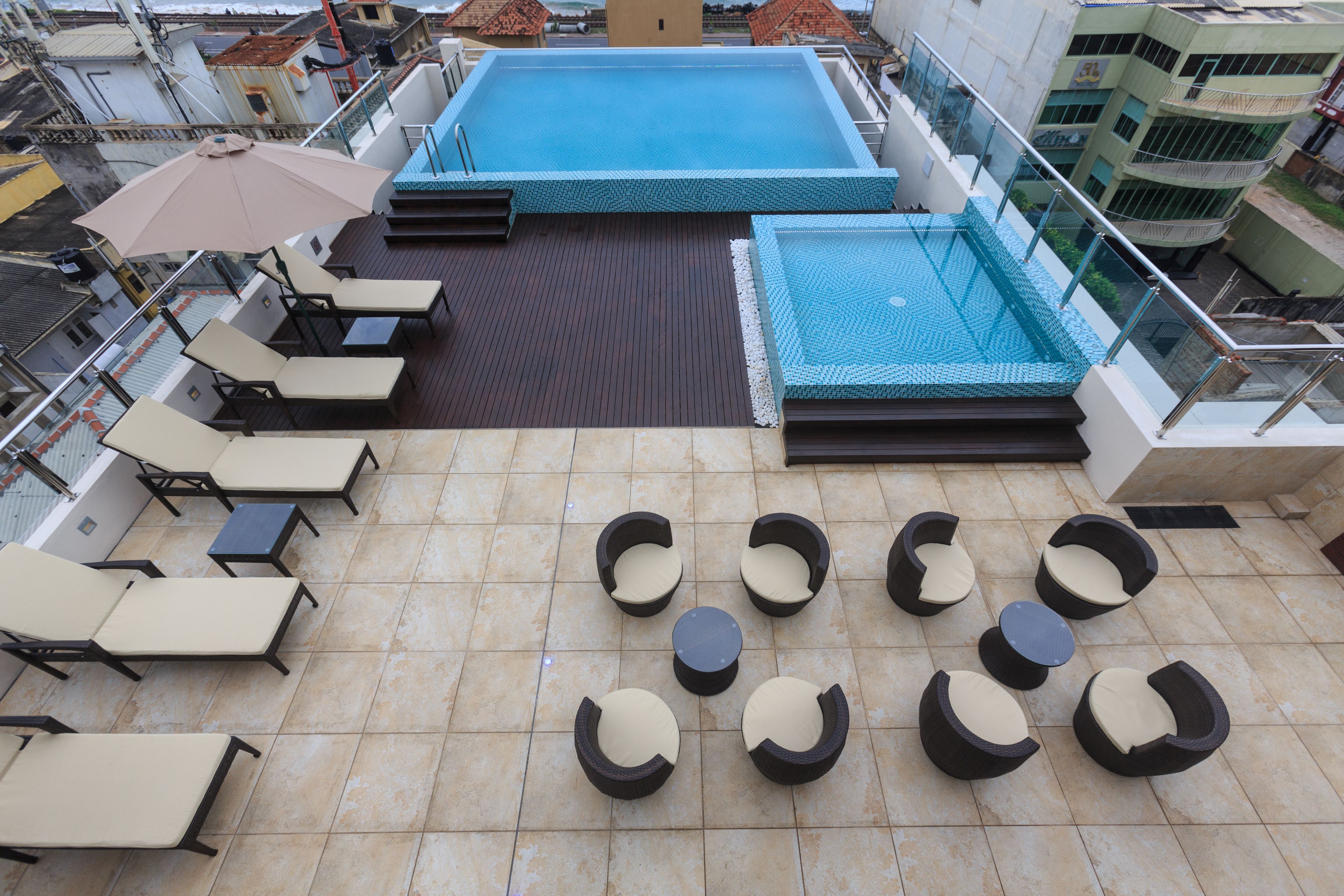 Un área de piscina en la azotea con sillones y una pequeña mesa.