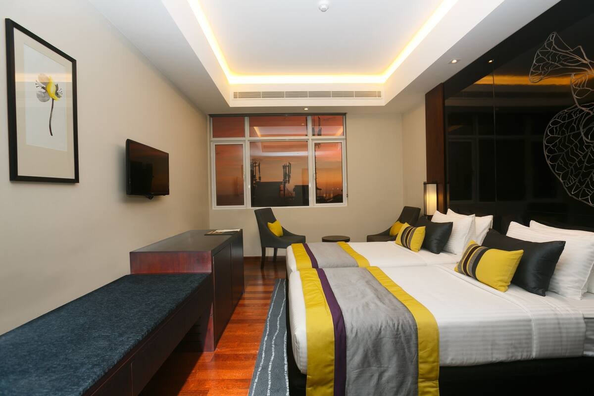 A hotel room with a large bed, a desk, a chair, and a TV.
