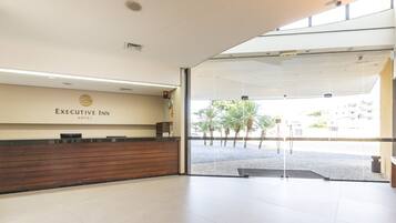 Un área de recepción con un mostrador de madera y una puerta de vidrio que da al exterior.