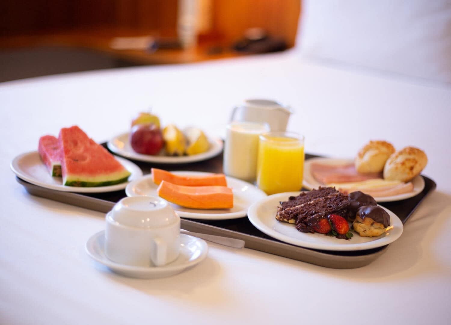 Bandeja de desayuno con sandía, fruta, jugo y pastelería.