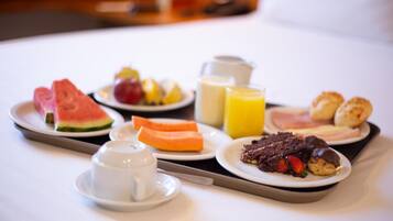 Bandeja de desayuno con sandía, fruta, jugo y pastelería.