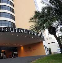 El exterior del Hotel Executive Inn, con un letrero llamativo y una palmera en primer plano.