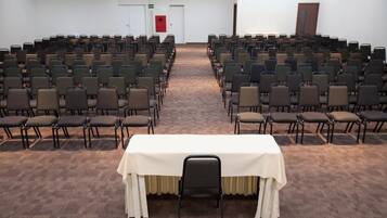 Un salón de conferencias con filas de sillas y una mesa en el centro.
