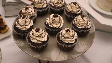 A tray of chocolate cupcakes with white frosting and chocolate drizzle.