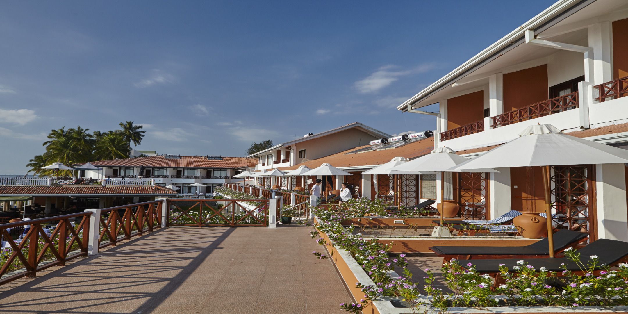Un hotel frente a la playa con terraza al aire libre y sombrillas, un área de piscina y vistas al océano.