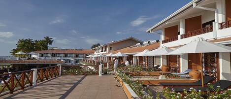 Un hotel frente a la playa con terraza al aire libre y sombrillas, un área de piscina y vistas al océano.