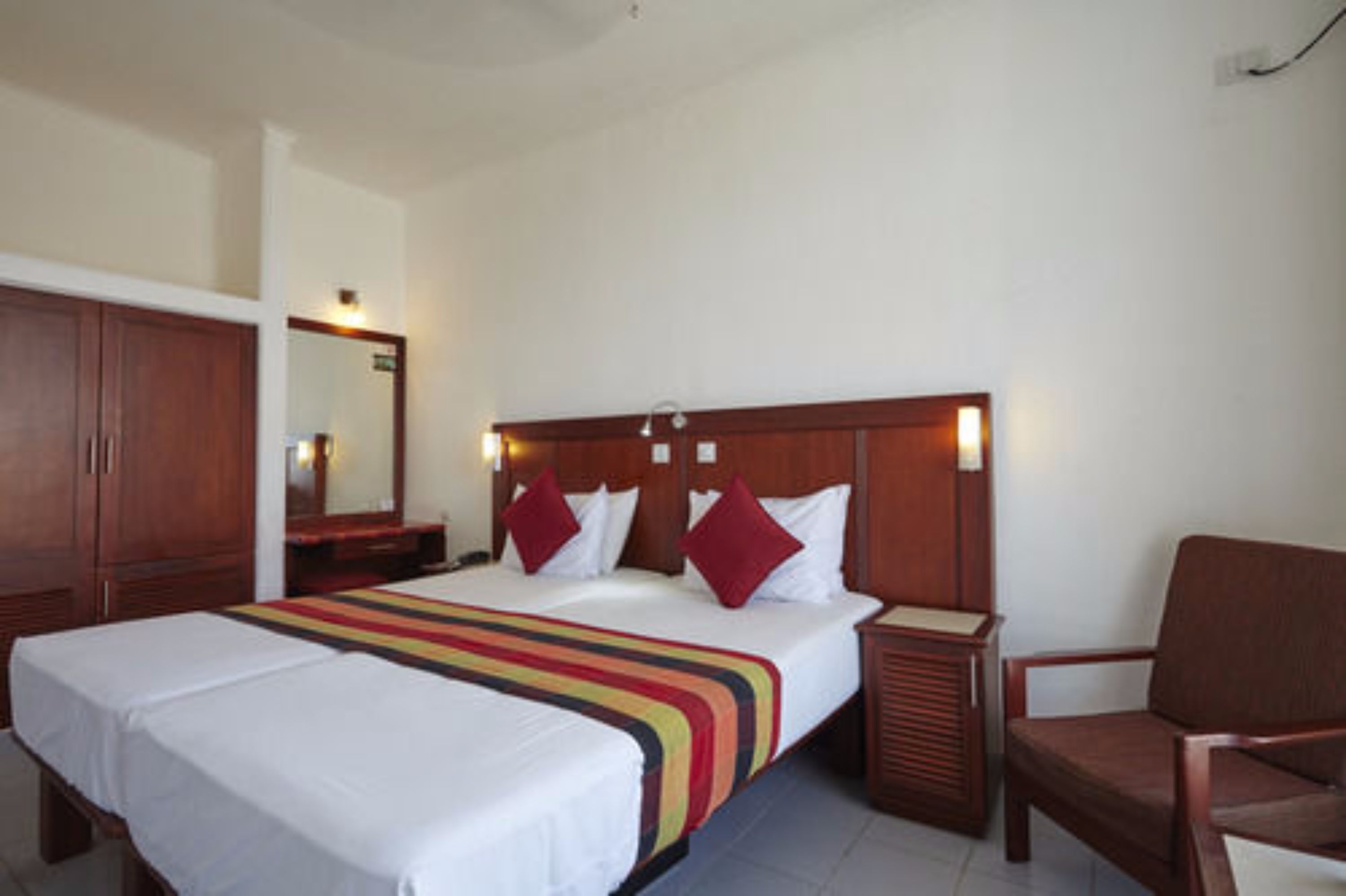A hotel room with a large bed, a wooden headboard, a nightstand, and a chair.