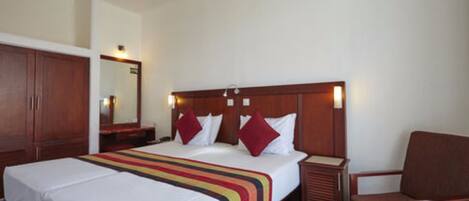A hotel room with a large bed, a wooden headboard, a nightstand, and a chair.