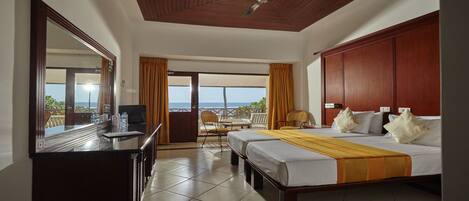 A hotel room with a bed, a desk, a chair, and a view of the ocean.