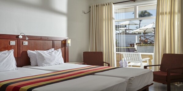 Una habitación de hotel con una cama grande, dos sillas, una mesita y una ventana con cortinas.