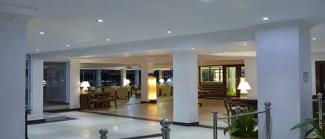 A spacious lobby with a reception desk, seating area, and a staircase leading to upper floors.