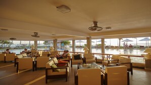 A spacious indoor area with comfortable seating and large windows overlooking a pool area. - Coral Sands Hotel (Hikkaduwa)