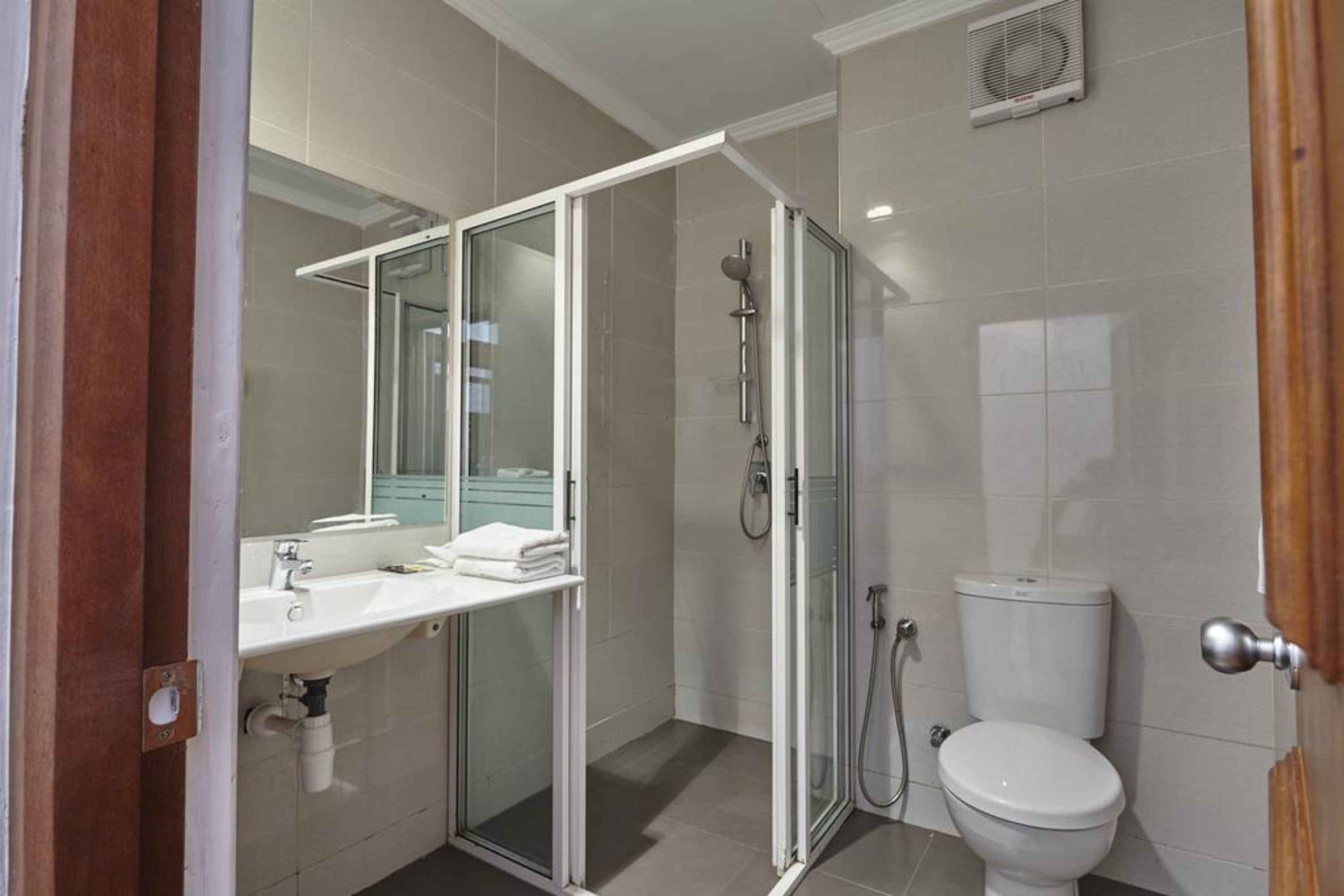 A modern bathroom with a glass shower enclosure, a white sink with a mirror, and a toilet.