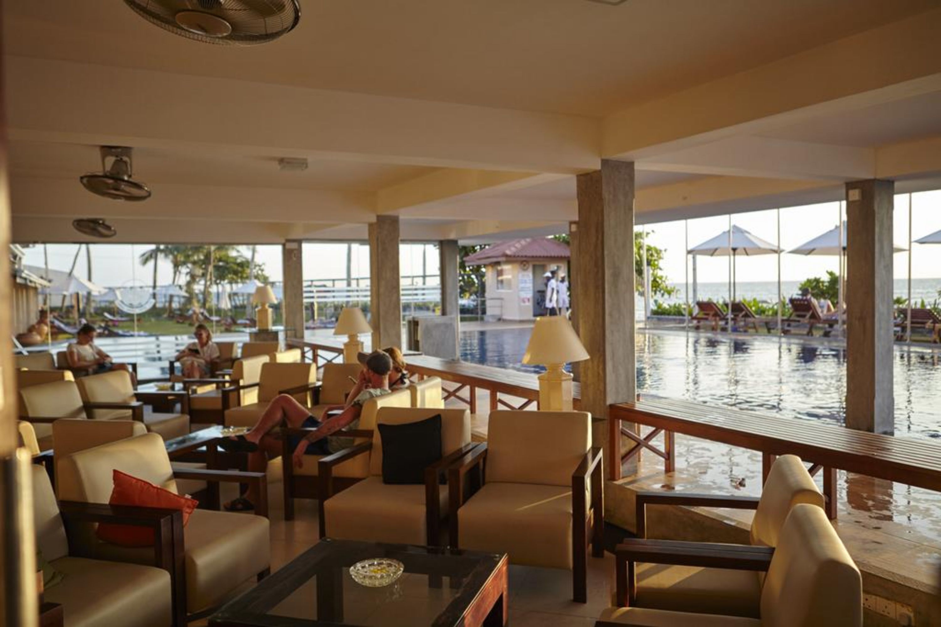 A hotel lobby with a pool view, comfortable seating, and a bar area.