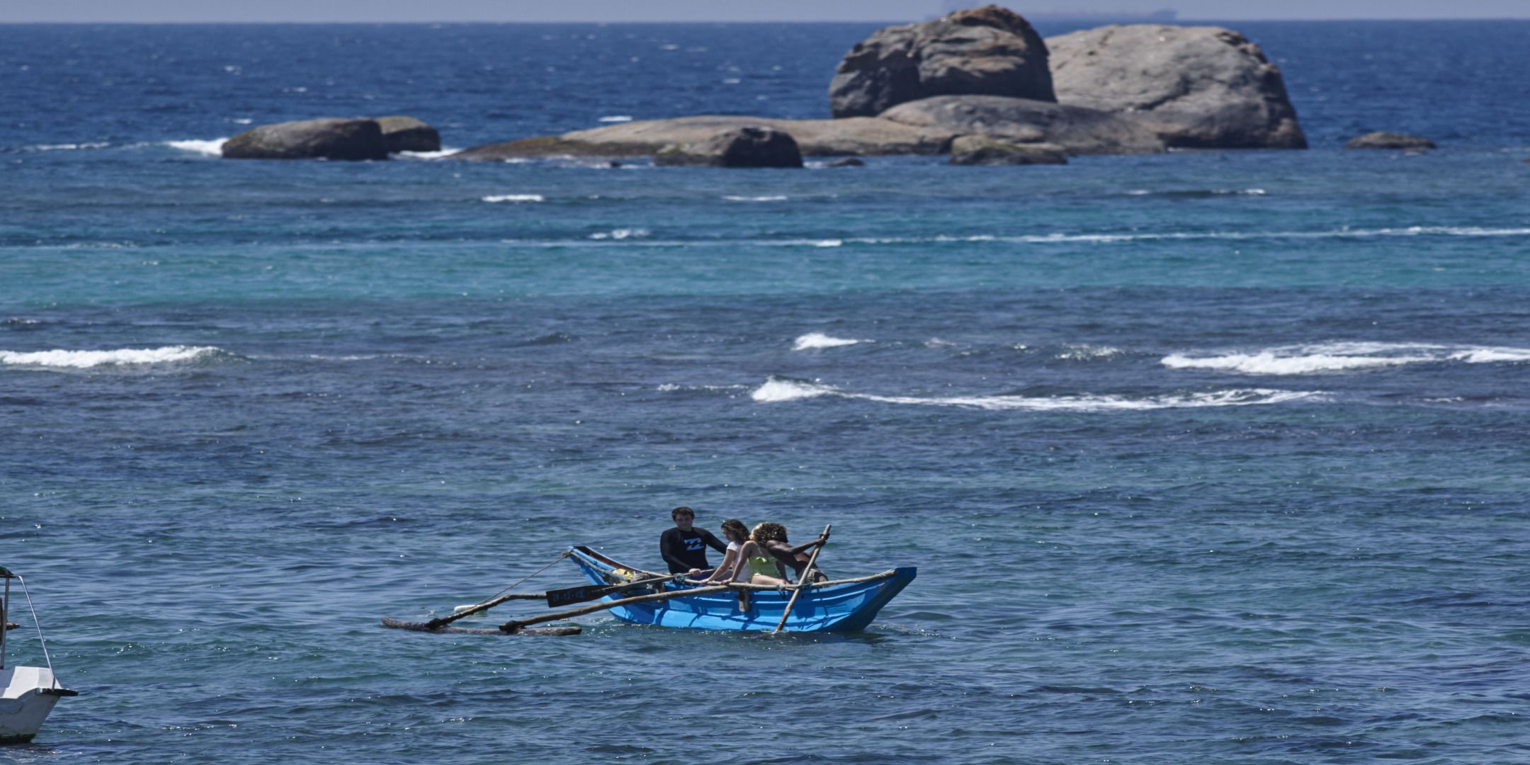 Un pequeño barco con tres personas en un mar tranquilo.