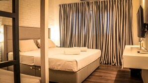A hotel room with a bed, a bedside table, a mirror, and a window with striped curtains. - Clock Inn Colombo (Colombo)