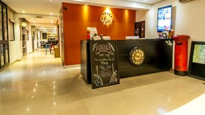 A hotel reception desk with a chalkboard sign detailing dinner night offerings, a clock, and a digital screen. - Clock Inn Colombo (Colombo)