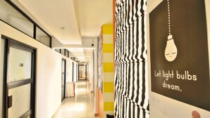 A modern hotel corridor with a long hallway, glass doors, and a wall with a light bulb illustration and text. - Clock Inn Colombo (Colombo)