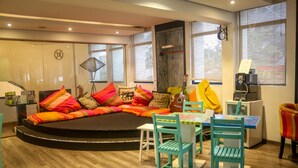 A cozy living area with a sofa adorned with colorful cushions, a small table with chairs, and a television. - Clock Inn Colombo (Colombo)