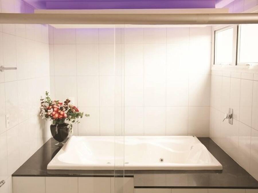A modern bathroom with a white bathtub, a black countertop, and a vase of flowers.