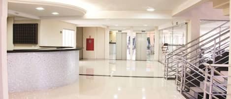 Un vestíbulo amplio con mostrador de recepción, una escalera y un piso limpio y pulido.