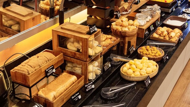 Un bufé con diversos productos de panadería y una máquina de café.